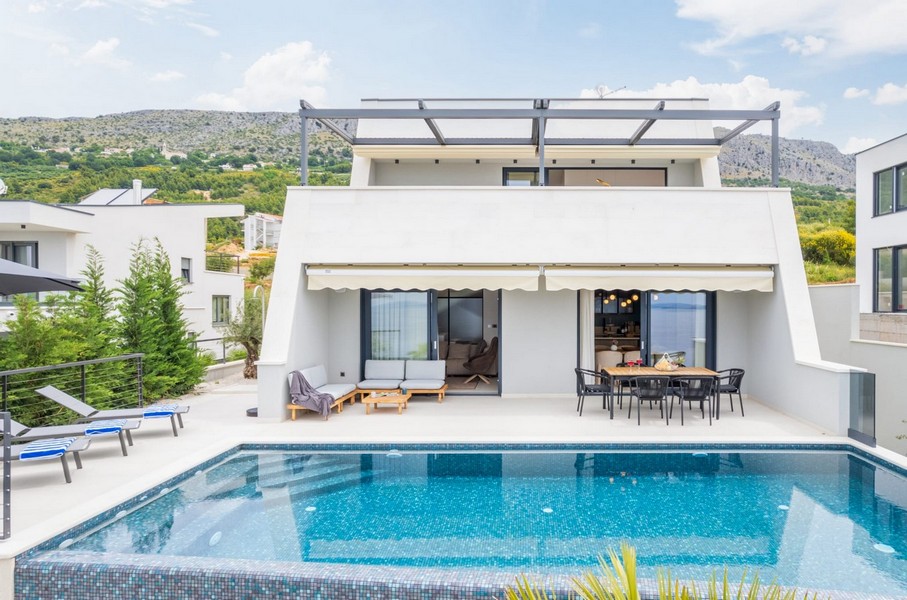 Villa blanche avec piscine et store au-dessus de la terrasse