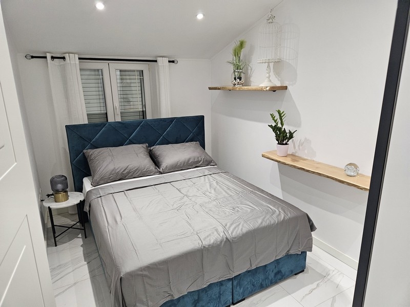 Chambre agréable avec tête de lit bleue et plantes décoratives dans un bien en Croatie
