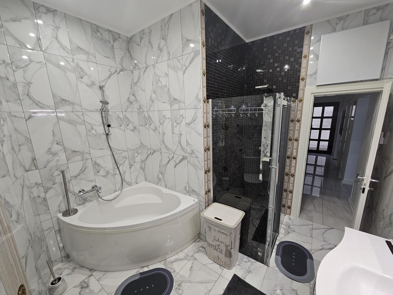 Élégante salle de bains aspect marbre avec combinaison baignoire-douche dans un bien croate