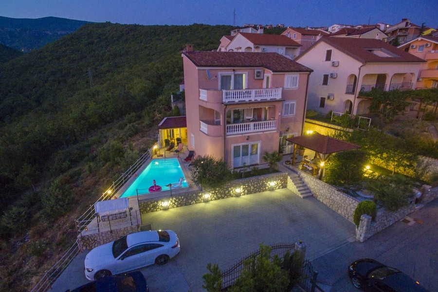 Vue du soir d'une maison à plusieurs logements en bord de mer en Croatie avec piscine éclairée - biens immobiliers Croatie