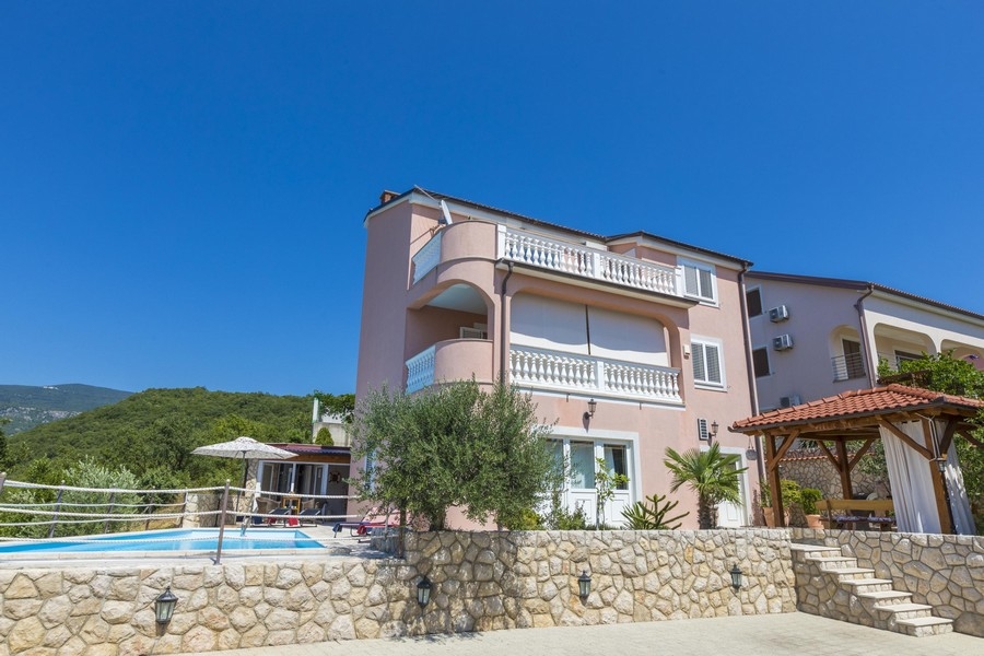 Vue de jour d'une maison à plusieurs logements rose en Croatie avec piscine
