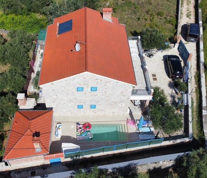 Vue aérienne d'une maison en pierre en vente en Croatie, avec jardin et piscine.