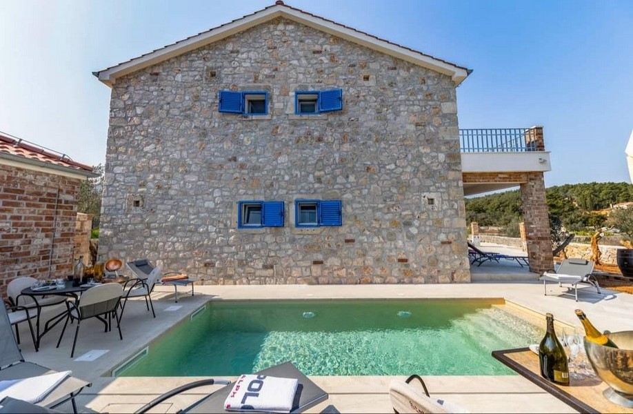 Vue arrière d'une villa en pierre croate à vendre avec piscine privée et coin barbecue.