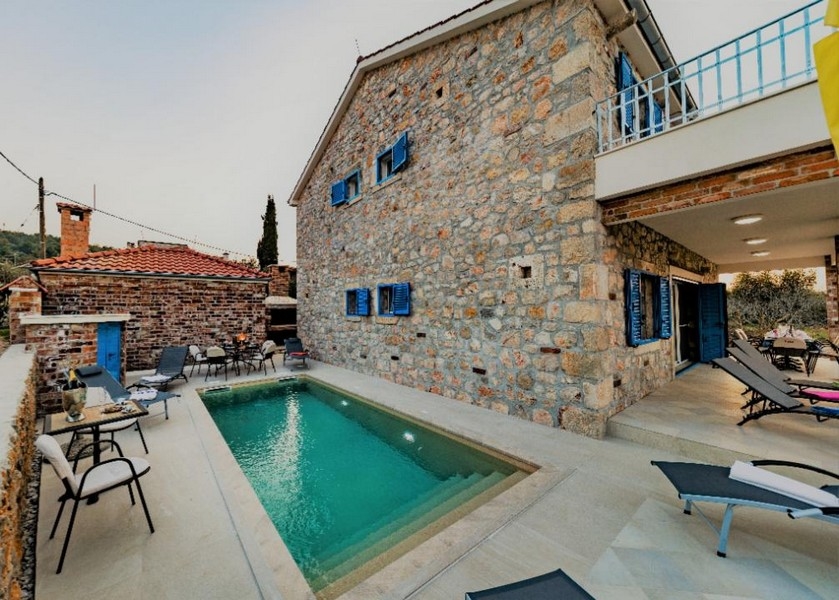Maison en pierre de luxe en Croatie à vendre avec espace lounge au bord de la piscine et environnement calme.