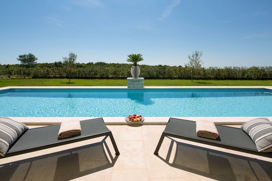 Espace de détente au bord de la piscine d'une villa de luxe en Croatie, entourée de nature et de calme
