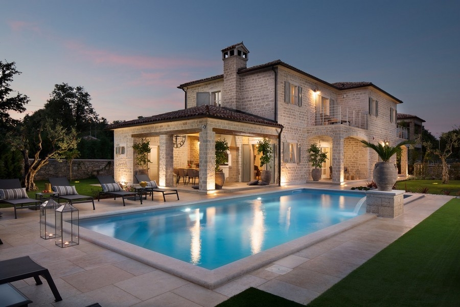 Villa de luxe en Croatie au crépuscule avec piscine éclairée et chaises longues.