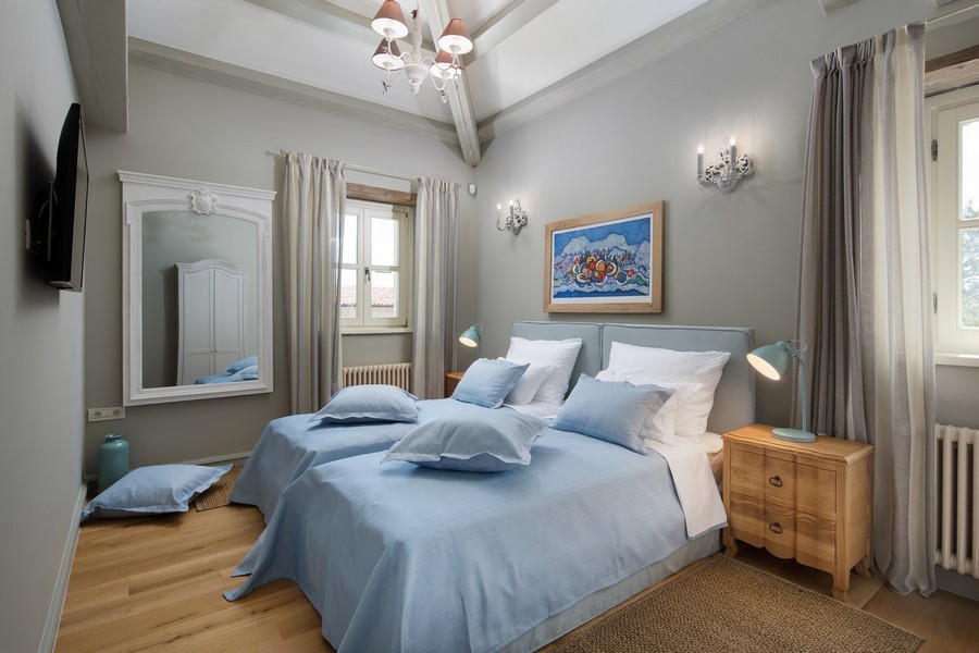 Chambre confortable dans une villa croate avec linge de lit bleu et parquet.