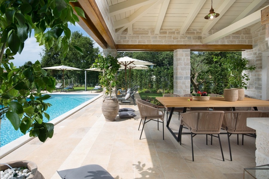 Terrasse couverte d'une villa croate avec table à manger et vue sur la piscine.