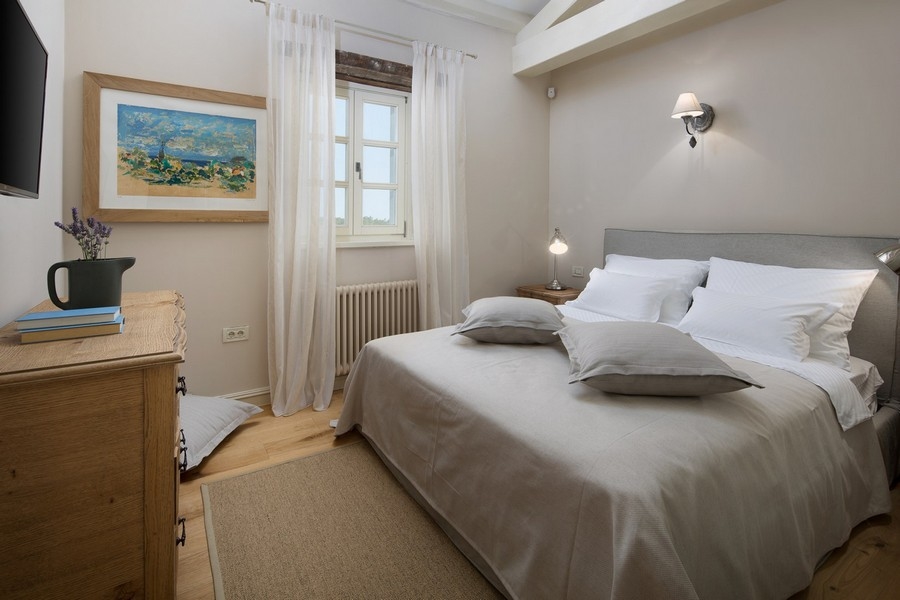 Chambre avec linge de lit neutre et meubles en bois dans la villa