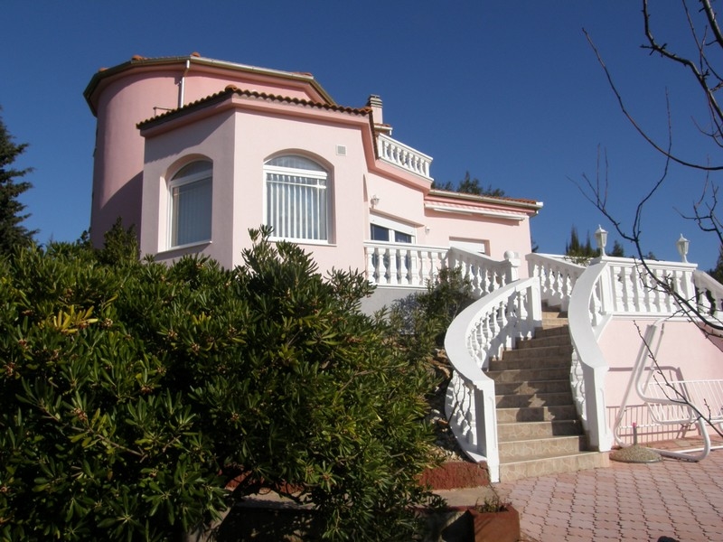 Villa rose en Croatie à vendre avec garde-corps blancs et escalier entouré de plantes vertes