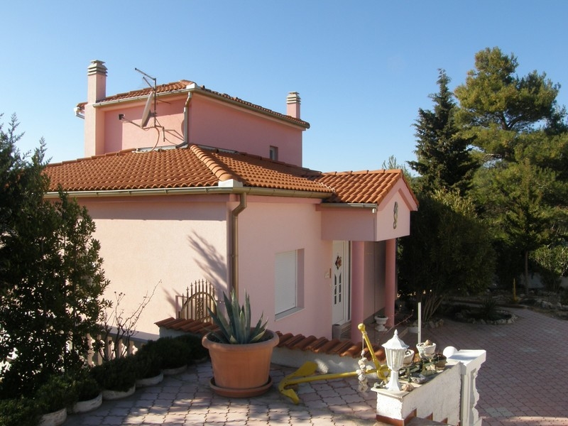 Arrière de la villa croate rose avec terrasse et entourée d'arbres