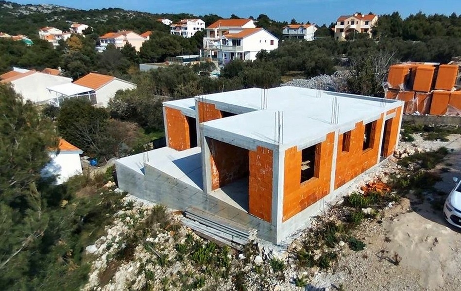 Vue de détail de la construction d'une villa avec murs en briques non enduits et piliers en béton, en vente sur l'île de Krk en Croatie