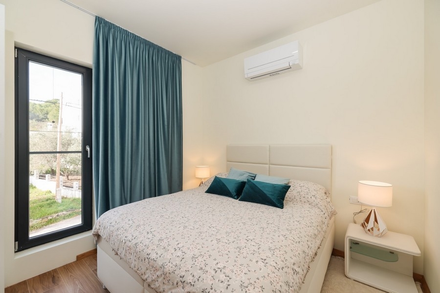 Chambre avec lit double, couleurs claires et vue par la fenêtre