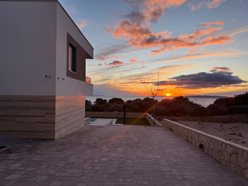 Vue sur la villa, les places de parking et la mer.