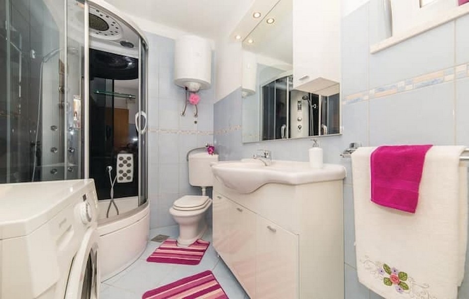 Salle de bains avec cabine de douche et lave-linge dans l'immeuble de rapport à Kaštel Lukšić, Croatie