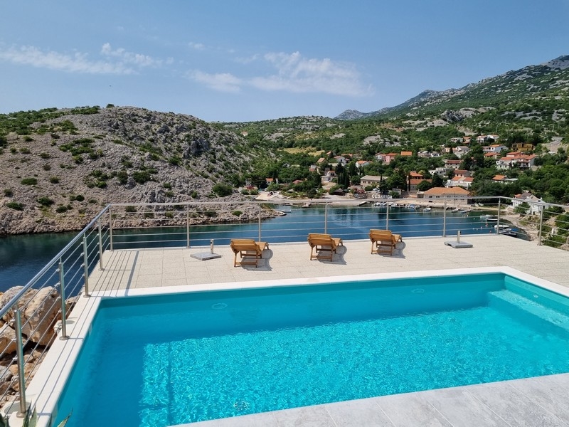 Piscine et terrasse avec transats et vue sur la baie