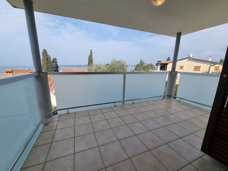 Loggia avec sol carrelé et vue sur les cyprès et la baie