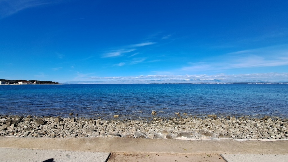 Plage de galets et mer claire devant un bien en bord de mer en Croatie