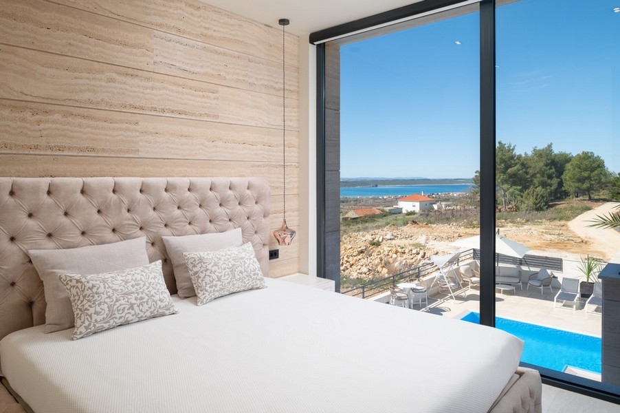 Chambre élégante dans une villa à vendre à Razanac, région de Zadar, Croatie, avec grand lit et tête de lit, vue mer et accès à l'espace piscine.