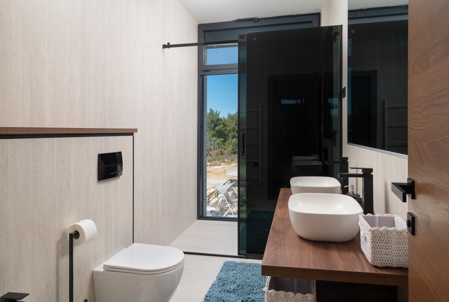 Salle de bains stylée avec vue mer dans une villa à vendre à Razanac, région de Zadar, Croatie, équipée d'un WC suspendu et d'une vasque moderne sur un meuble bas en bois.