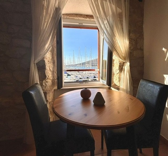 Pièce mansardée avec vue sur le port par une fenêtre dans un bien en Croatie