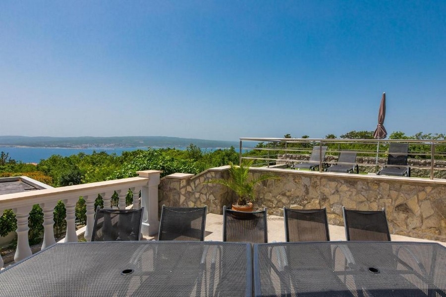 Terrasse d'un immeuble collectif en Croatie avec table et chaises, vue mer à l'arrière-plan