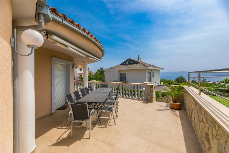 Grande terrasse d'un immeuble collectif en Croatie avec longue table et chaises, vue mer