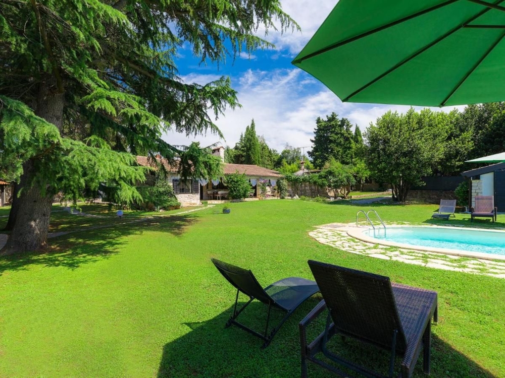 Jardin idyllique avec chaises longues et vue sur un ensemble de bâtiments en pierre, représentatif des biens immobiliers en Croatie