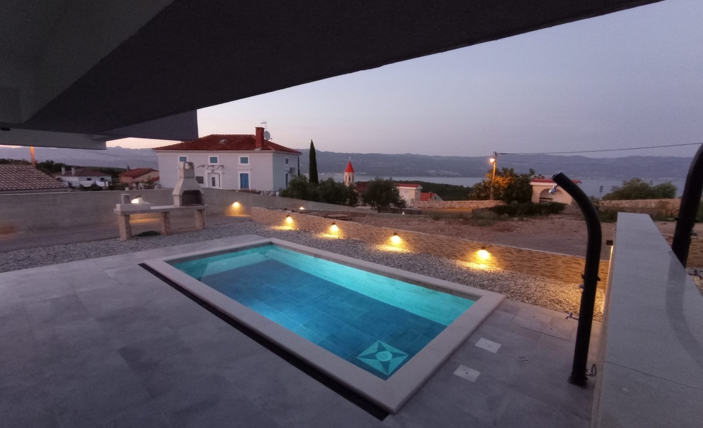 Vue du soir d'un bien en Croatie avec piscine éclairée et la mer à l'arrière-plan.