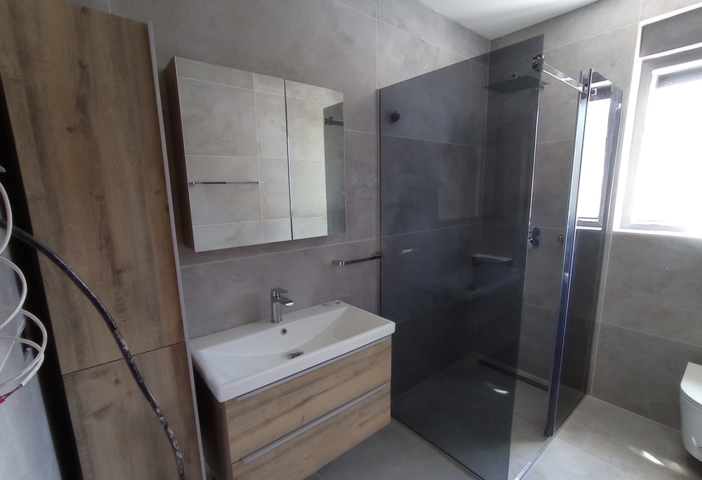 Salle de bains moderne avec douche à l'italienne dans un bien en Croatie, armoire à miroir et éléments en bois dans le design.