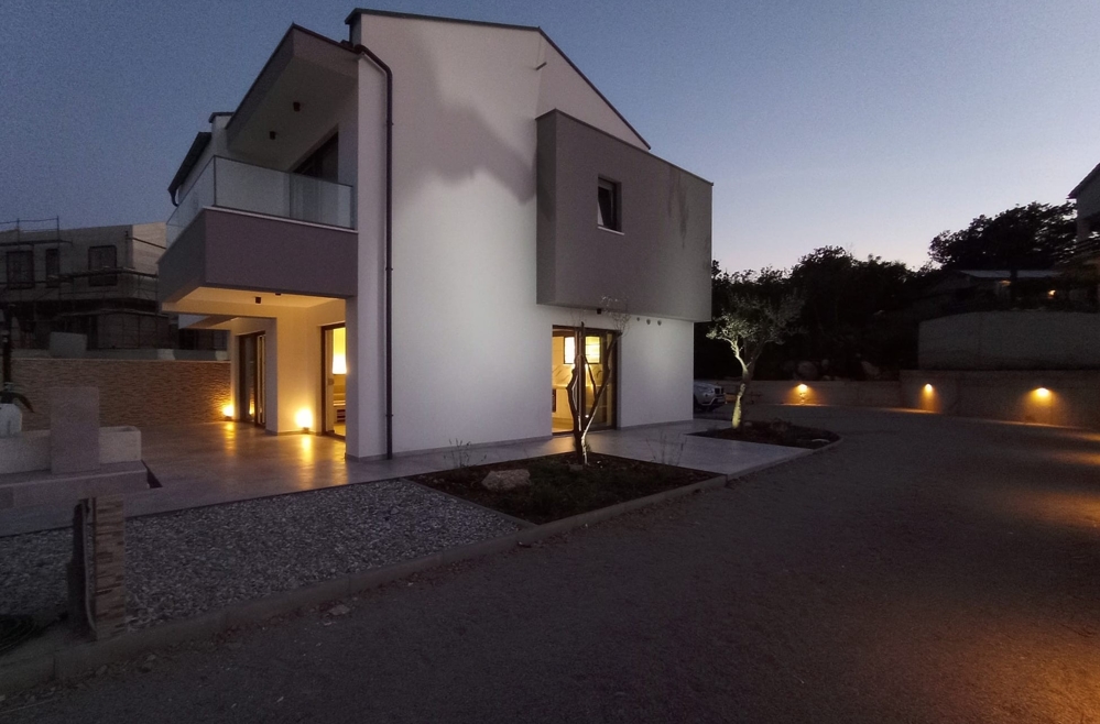 Vue latérale d'un bien en Croatie au crépuscule avec chemin éclairé et entrée.