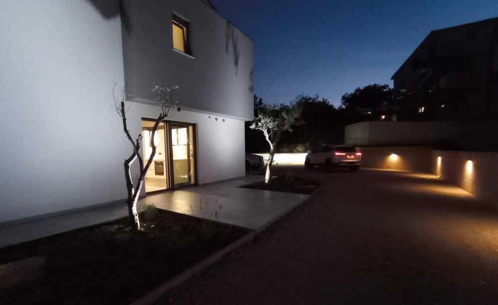 Photo de nuit d'un bien en Croatie avec éclairage extérieur et voiture garée dans la cour.