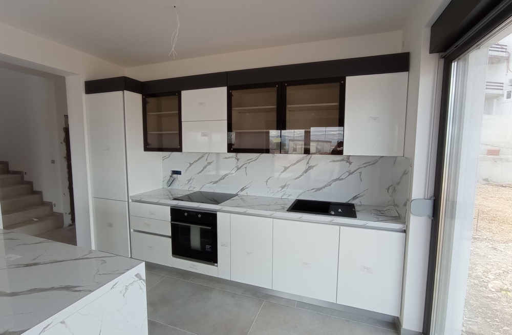 Vue intérieure d'une cuisine moderne avec meubles blancs dans un bien en Croatie.