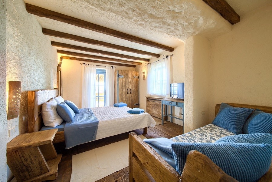 Chambre agréable avec meubles rustiques en bois et éclairage naturel, aspect accueillant du bien sur l'île de Krk.