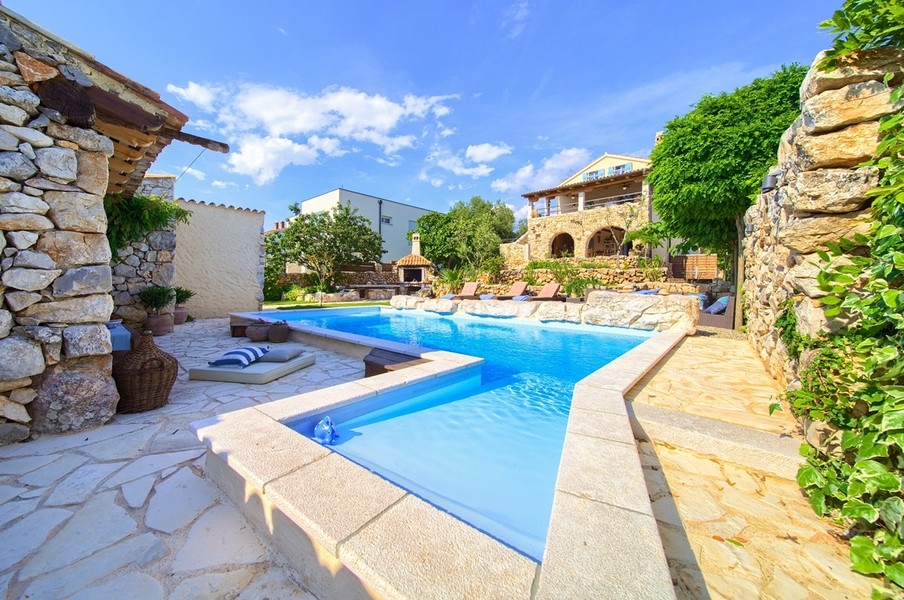 Piscine avec terrasse en pierre naturelle et vue sur la maison en pierre