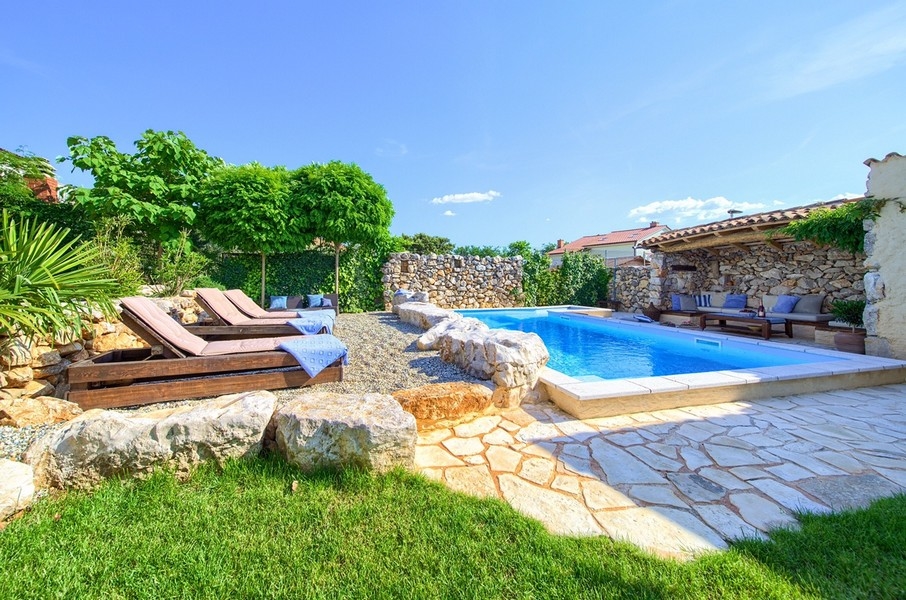 Espace jardin entretenu avec piscine et chaises longues, partie de l'offre du bien sur l'île de Krk.