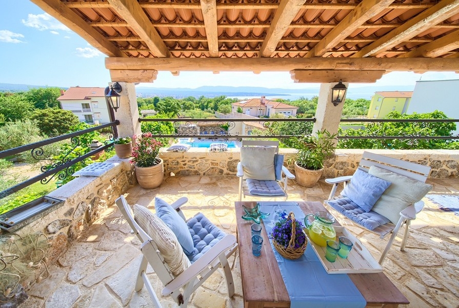 Terrasse couverte avec coin salon convivial et vue sur la mer, détail charmant du bien sur l'île de Krk.