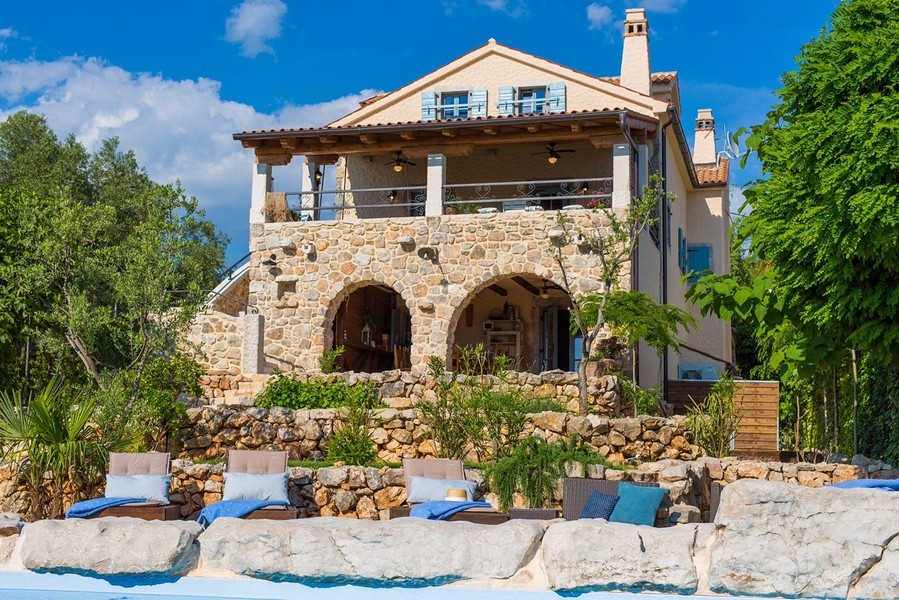 Vue de face d'une villa méditerranéenne avec piscine et arcs en pierre, représentative du bien sur l'île de Krk.