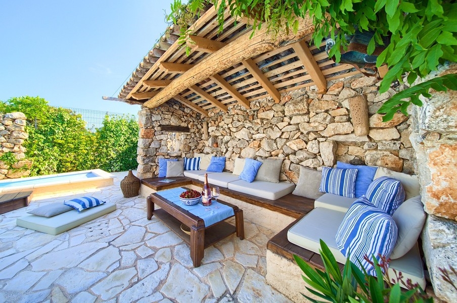 Coin salon extérieur couvert avec coussins confortables et vue sur la piscine, typique du bien sur l'île de Krk.