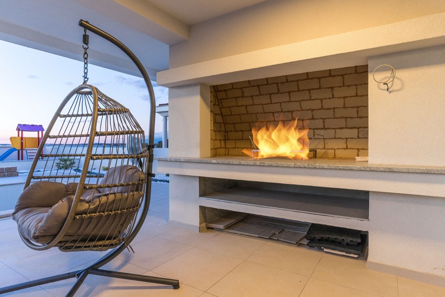 Villa de luxe moderne avec fauteuil suspendu et cheminée intégrée, parfaite pour une soirée agréable dans votre nouveau bien en Croatie.