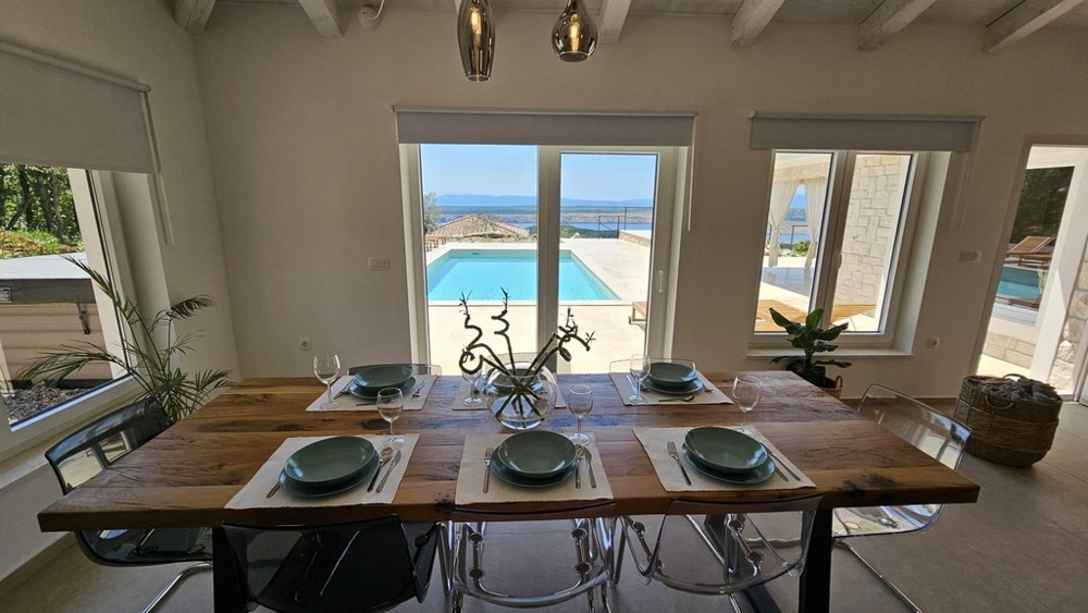 Coin repas avec vue sur la piscine et la mer.