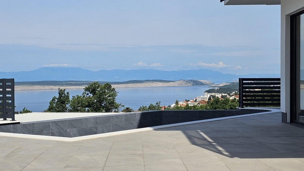 Terrasse vide avec garde-corps sombre et vue sur la baie