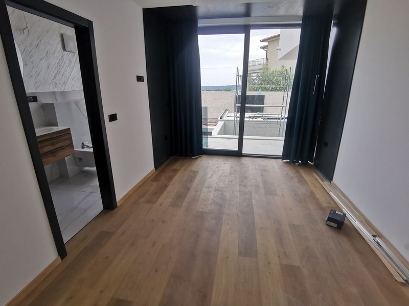 Chambre avec parquet et passage vers la salle de bains en marbre