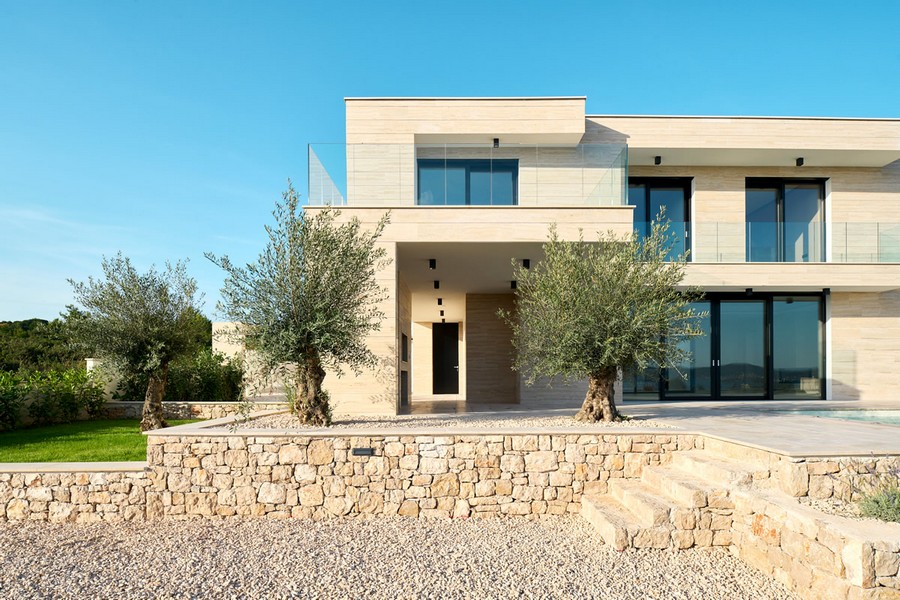 Villa avec façade en pierre et oliviers au-dessus du mur en pierre sèche