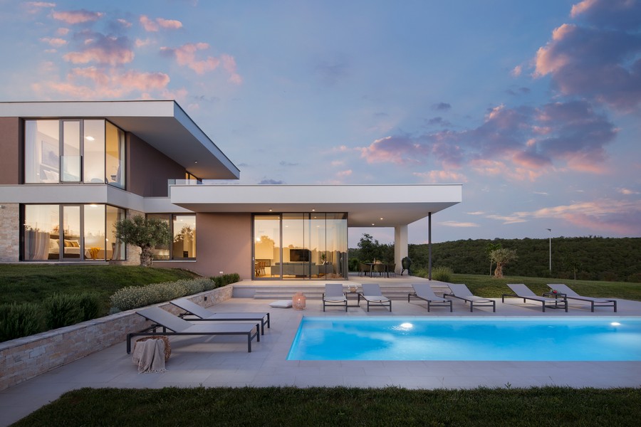 Villa avec piscine et transats sous des nuages roses du soir