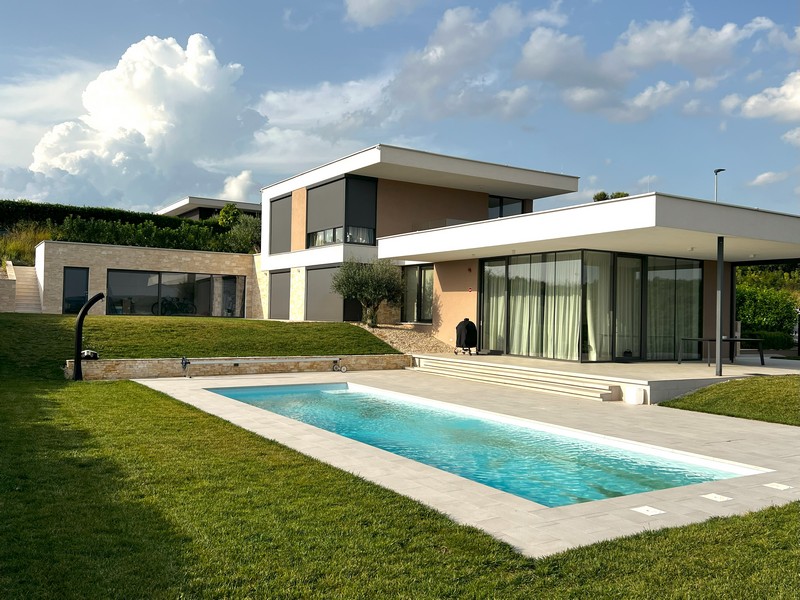 Longue piscine devant la villa sous des cumulus
