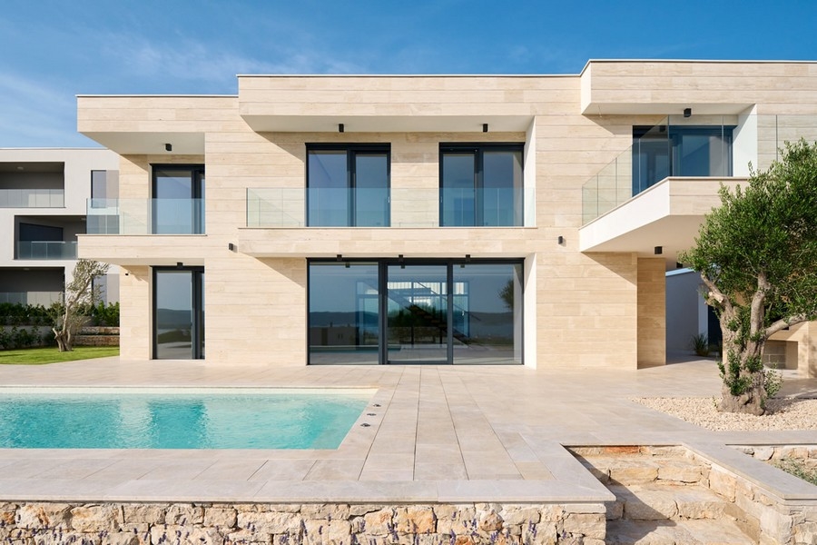 Villa avec façade en pierre claire et piscine derrière le mur en pierre sèche