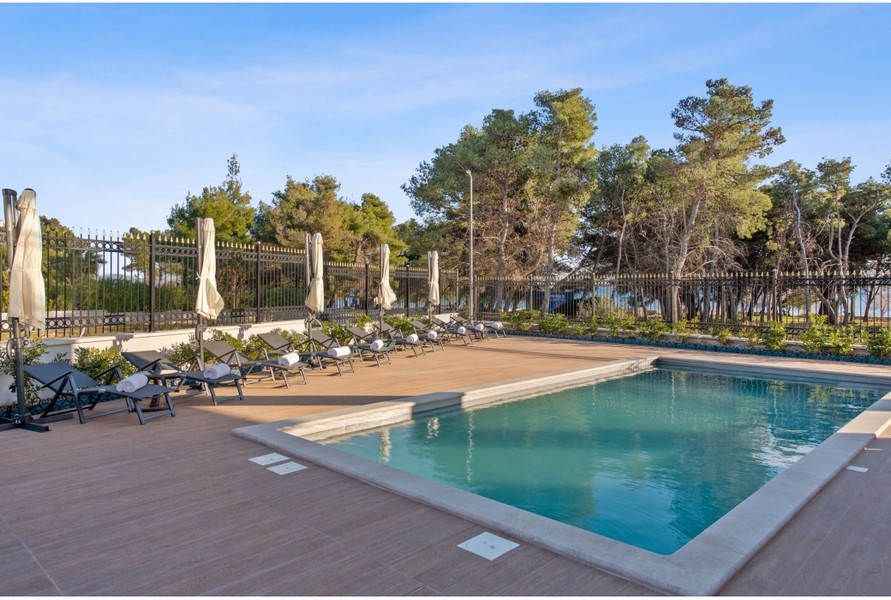Espace extérieur de la villa H3042 avec une piscine extérieure chauffée et des chaises longues, entouré de plantes méditerranéennes