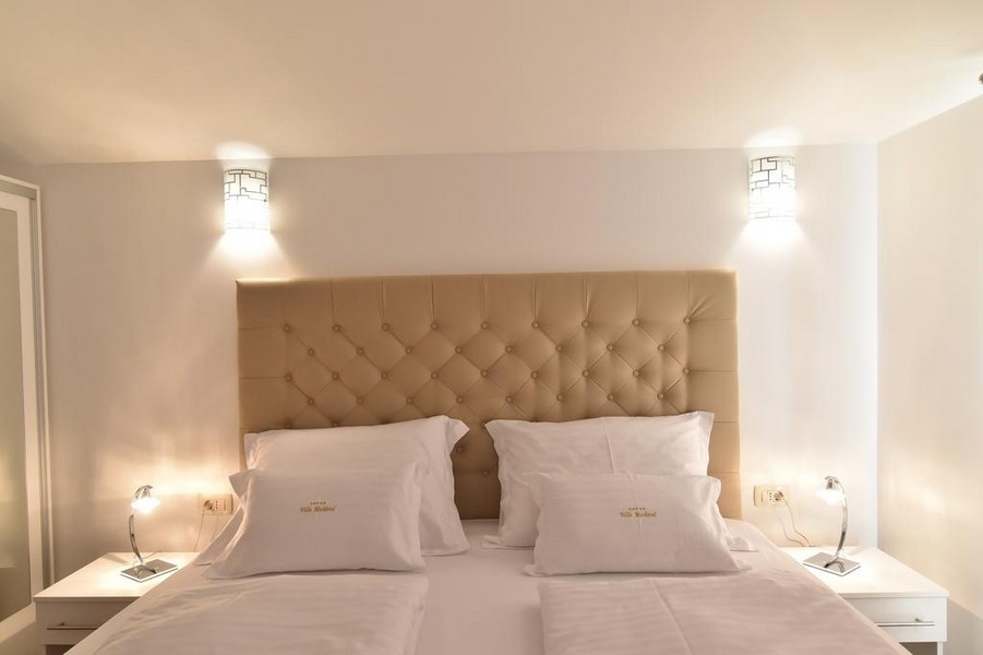Gros plan du lit dans la chambre avec éclairage moderne, proposé par l'agence immobilière Panorama Scouting