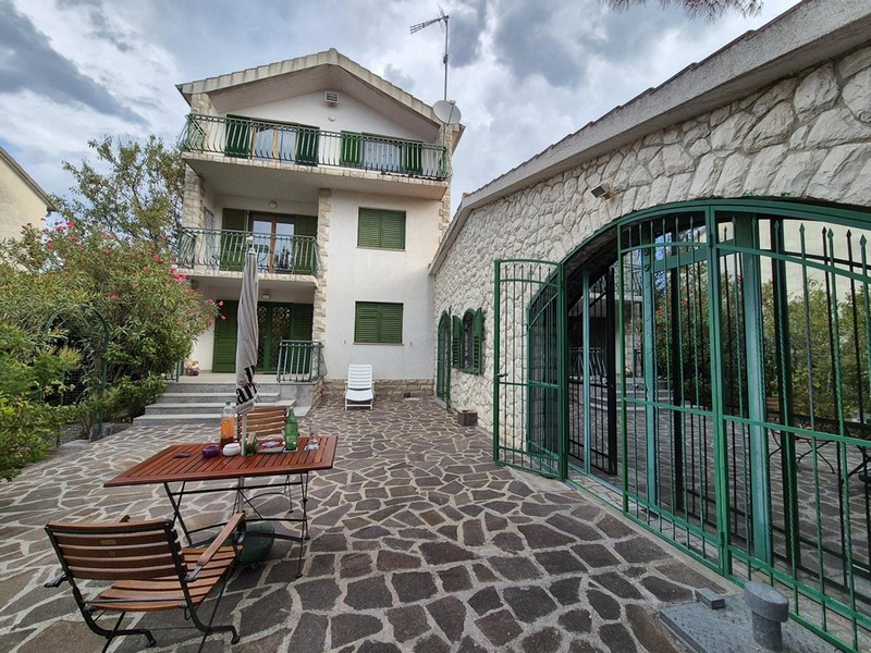 Maison avec volets verts et table de jardin dans la cour en pierre